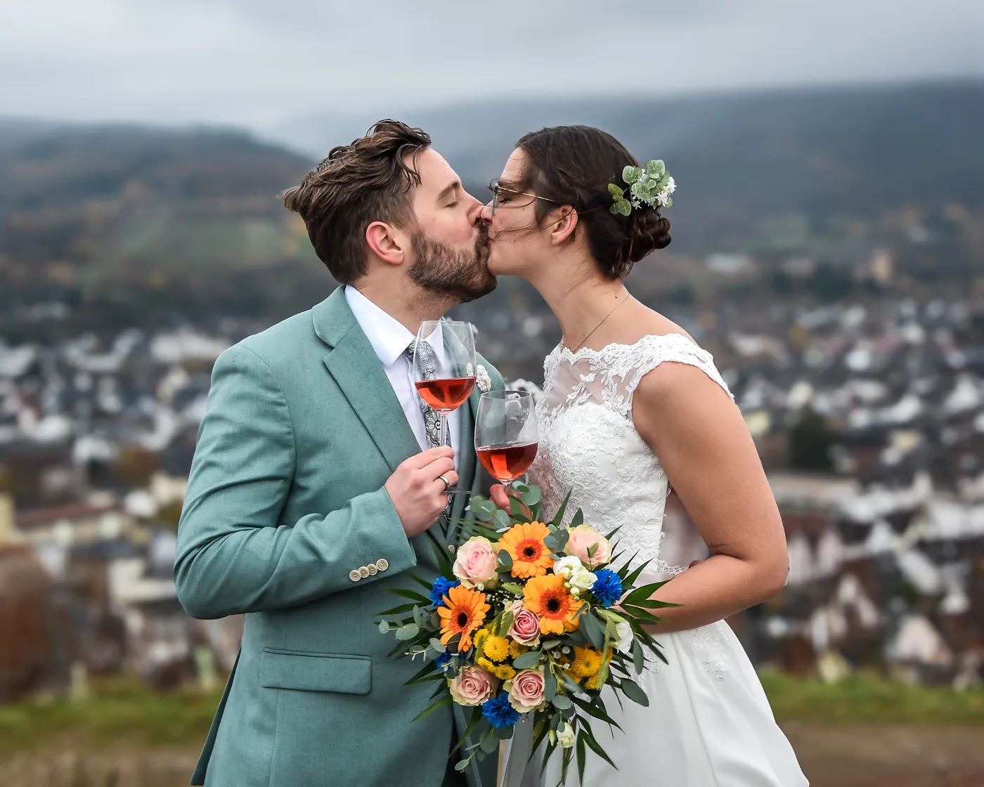 Brautpaar küsst sich mit Blumenstrauß